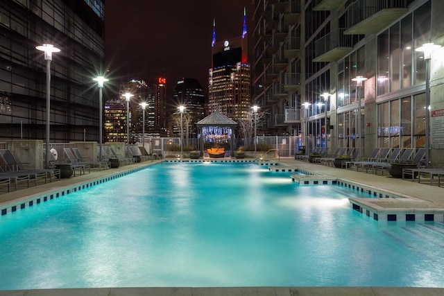 pool at twilight with a community pool and fence