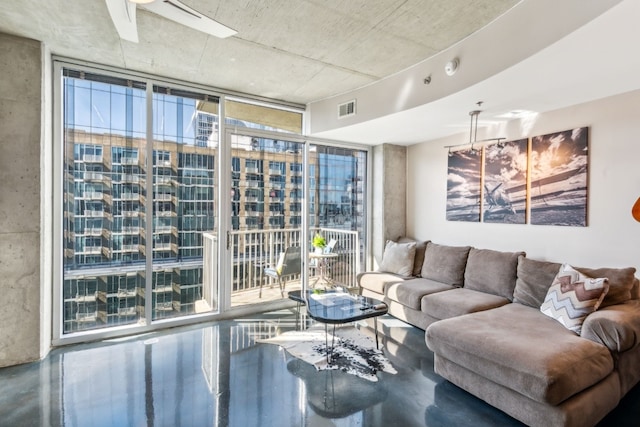 living area with a wall of windows, visible vents, and concrete floors