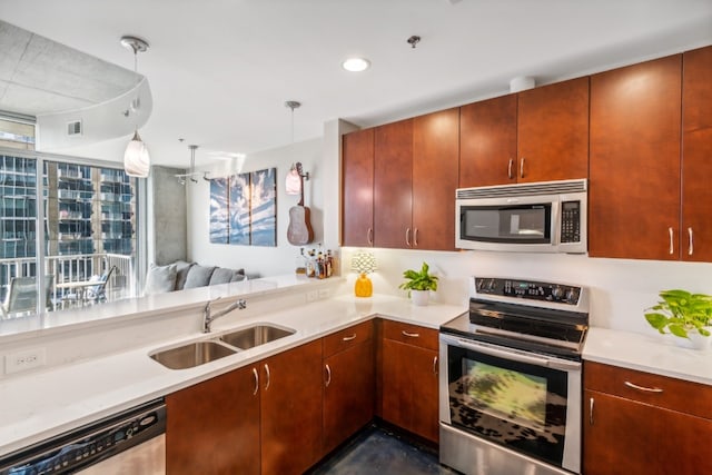 kitchen with appliances with stainless steel finishes, sink, kitchen peninsula, and hanging light fixtures