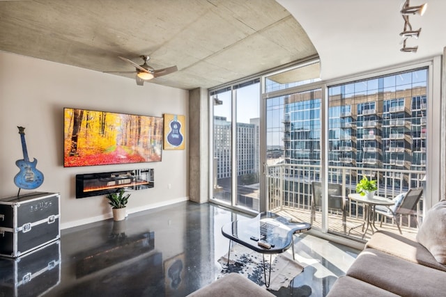 living room with baseboards, concrete floors, ceiling fan, floor to ceiling windows, and a glass covered fireplace