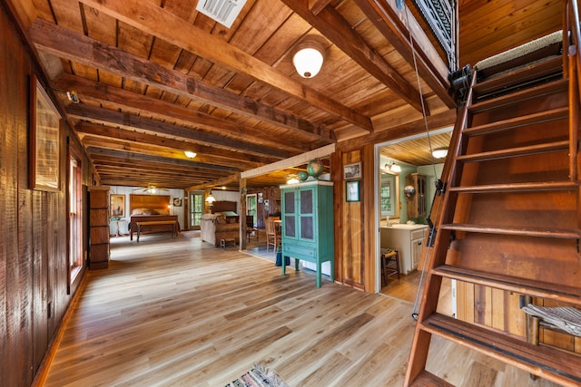 interior space featuring wood walls, wood ceiling, beamed ceiling, and light hardwood / wood-style flooring