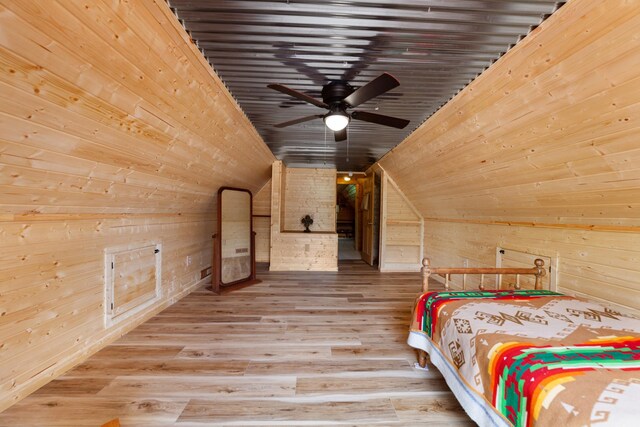 unfurnished bedroom with wood walls, wood-type flooring, vaulted ceiling, and ceiling fan