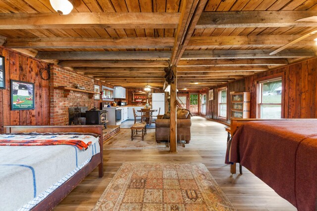 bedroom with light wood-type flooring, wood walls, beam ceiling, and wooden ceiling