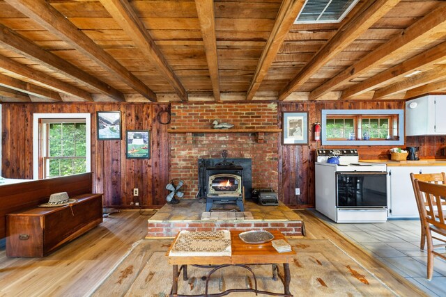 living room featuring a fireplace, wood walls, a wood stove, and light hardwood / wood-style floors