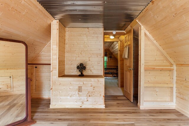 additional living space featuring hardwood / wood-style floors and wooden walls