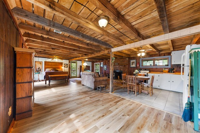 dining room featuring wooden ceiling, beam ceiling, light hardwood / wood-style floors, ceiling fan, and wooden walls