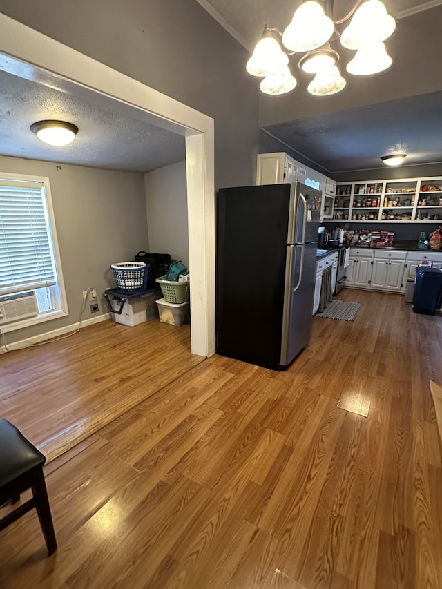 kitchen featuring stainless steel fridge, white cabinetry, light hardwood / wood-style flooring, and an inviting chandelier