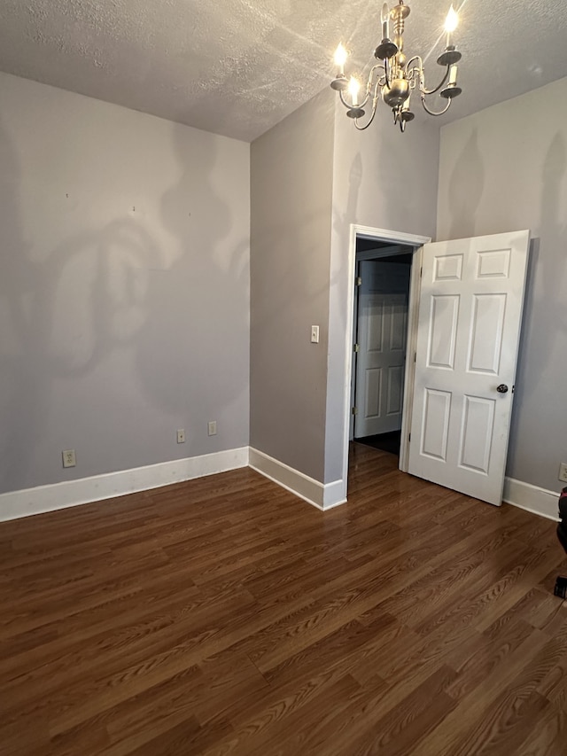 unfurnished bedroom featuring dark hardwood / wood-style floors, a chandelier, and a textured ceiling