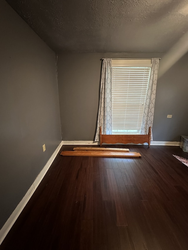spare room featuring a textured ceiling and wood-type flooring