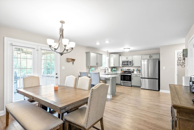 dining room featuring light wood-type flooring, an inviting chandelier, and sink