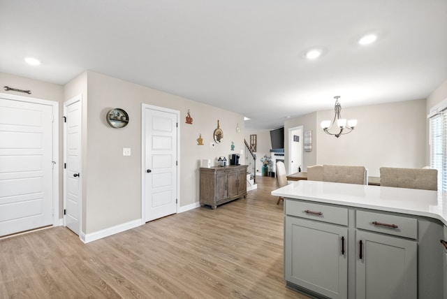 kitchen featuring light wood-type flooring, pendant lighting, gray cabinets, and a chandelier