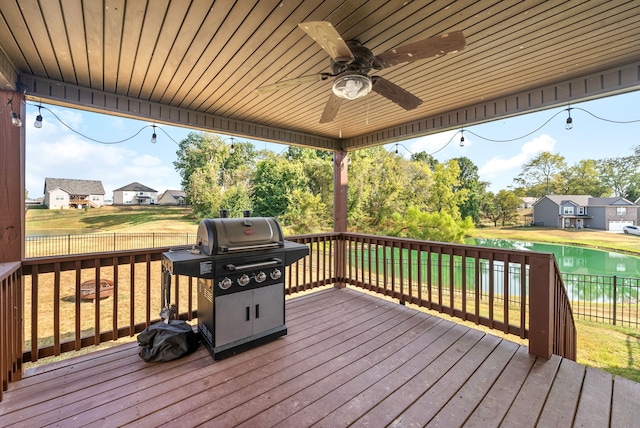 wooden terrace with area for grilling, a lawn, and ceiling fan