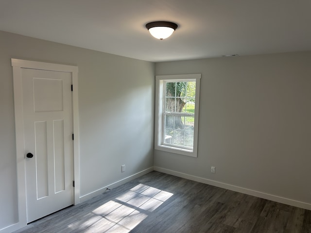 unfurnished room with dark wood-type flooring