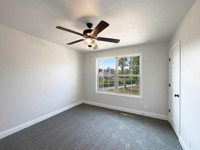 empty room with ceiling fan and dark colored carpet