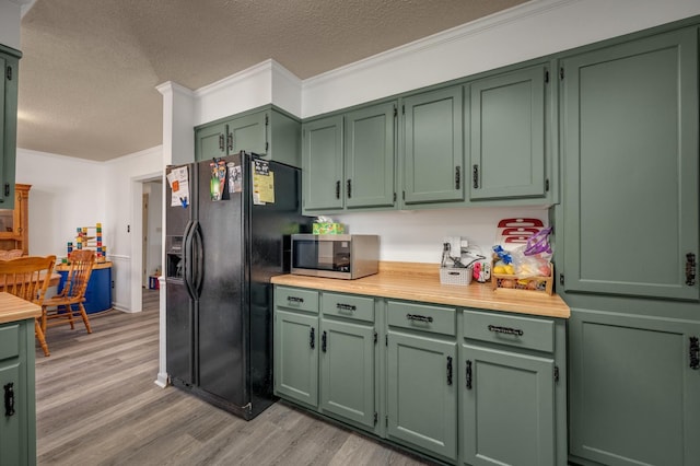 kitchen featuring light hardwood / wood-style flooring, green cabinets, ornamental molding, and black fridge with ice dispenser