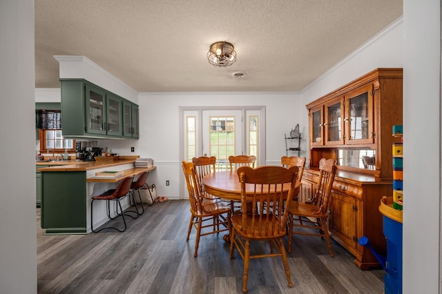 dining space featuring a textured ceiling, crown molding, and dark hardwood / wood-style flooring