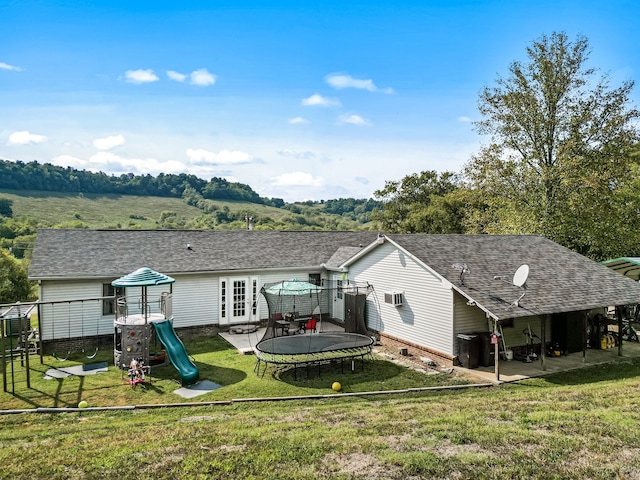 back of property featuring a lawn, a patio, a trampoline, and a playground