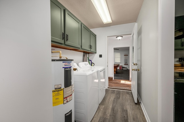 clothes washing area featuring cabinets, hardwood / wood-style floors, water heater, a textured ceiling, and washing machine and clothes dryer