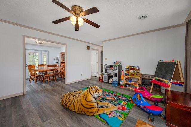 game room with ornamental molding, dark hardwood / wood-style flooring, ceiling fan, and a textured ceiling