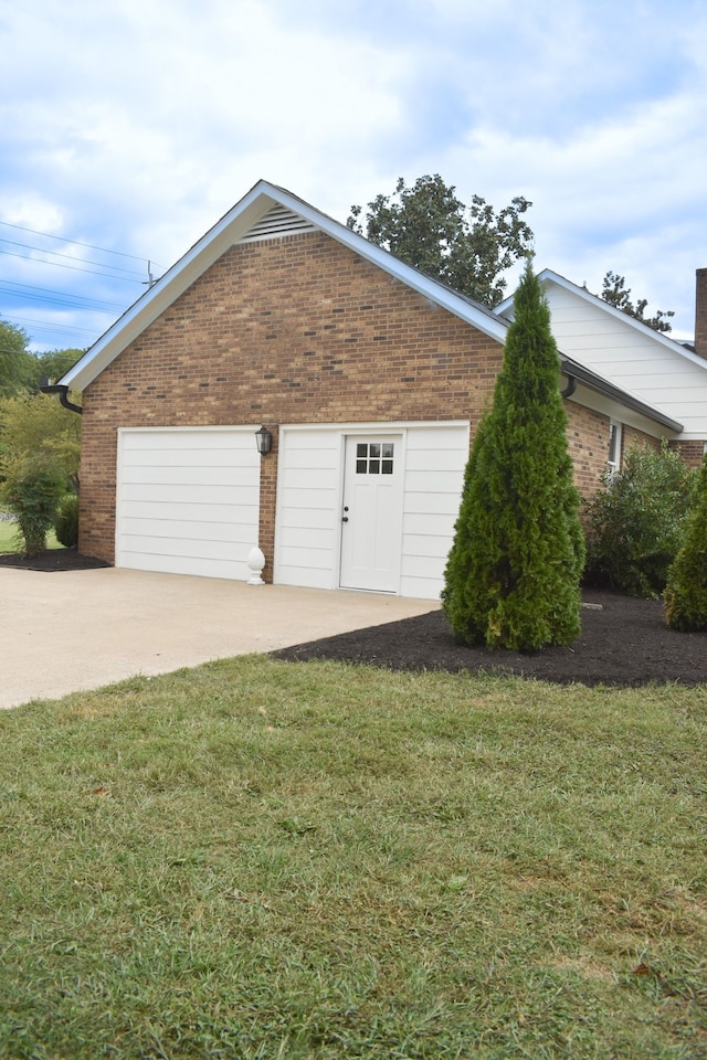 view of home's exterior with a garage, driveway, brick siding, and a lawn