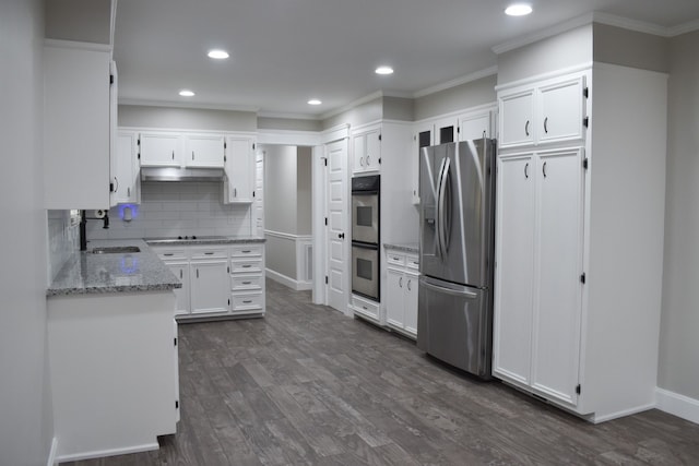 kitchen with light stone countertops, dark hardwood / wood-style flooring, appliances with stainless steel finishes, crown molding, and white cabinets