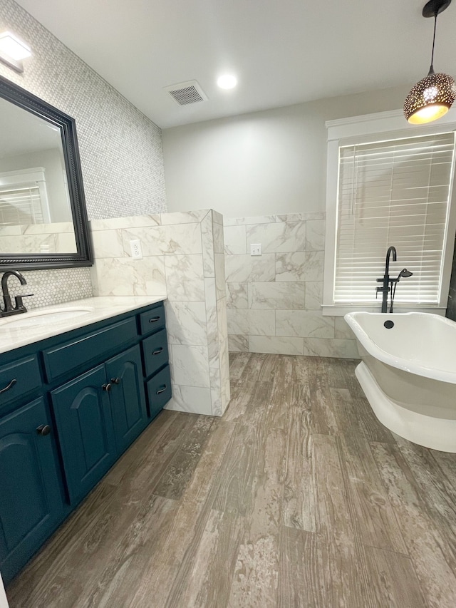 bathroom with vanity, tile walls, a bathtub, and wood-type flooring