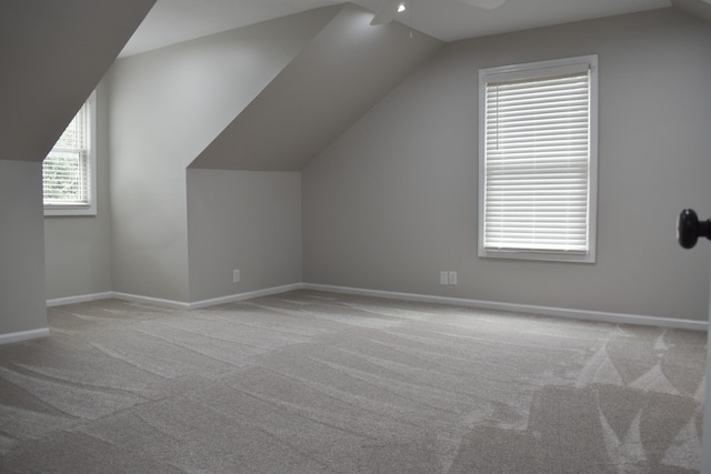 additional living space with lofted ceiling, light colored carpet, and ceiling fan