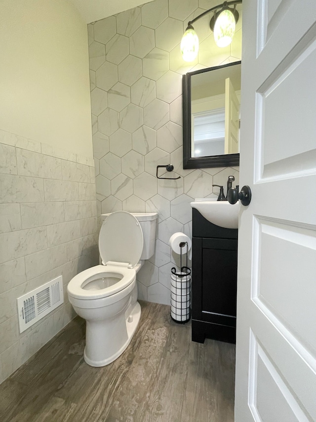 bathroom with vanity, toilet, hardwood / wood-style floors, and tile walls