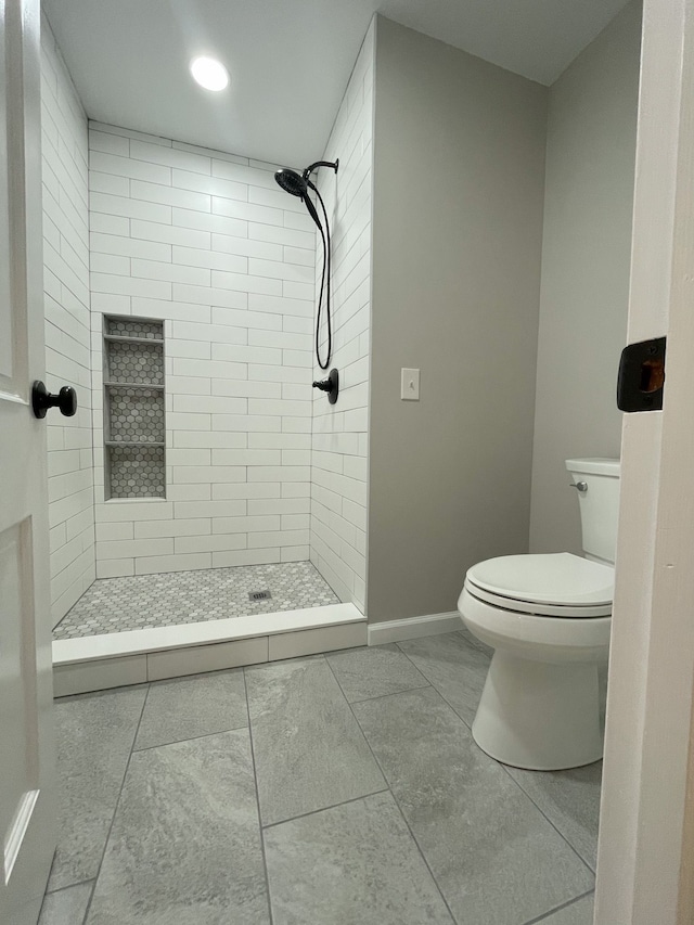 bathroom featuring tiled shower and toilet