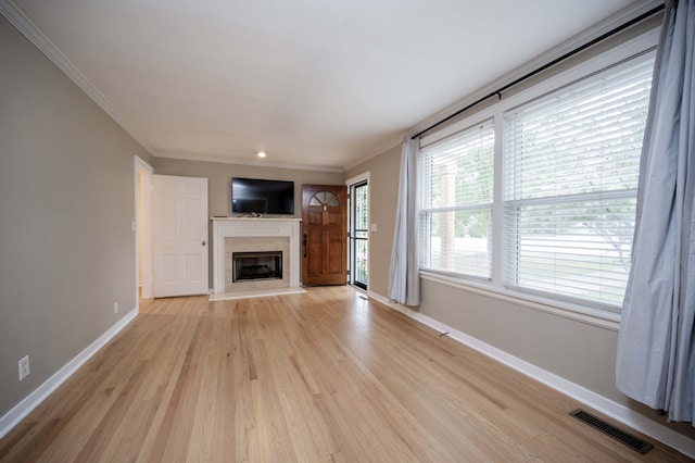 unfurnished living room featuring a fireplace, ornamental molding, and light hardwood / wood-style flooring