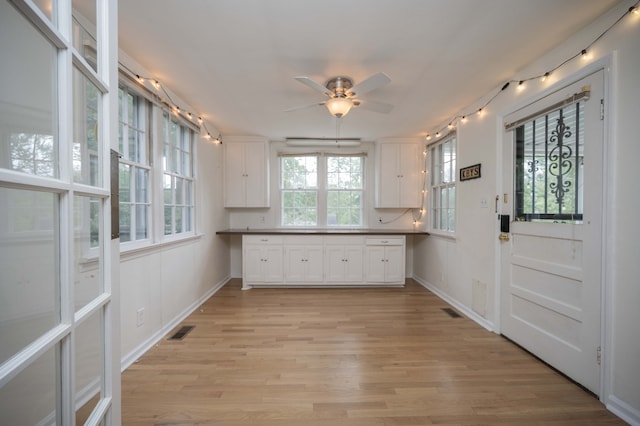 interior space featuring ceiling fan, light wood-type flooring, and white cabinetry