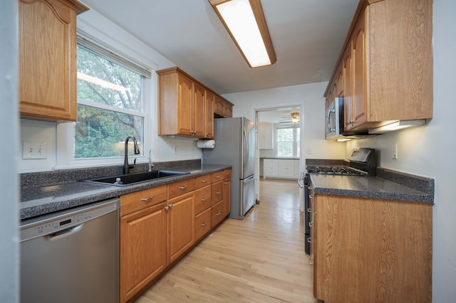 kitchen with stainless steel appliances, sink, and light wood-type flooring