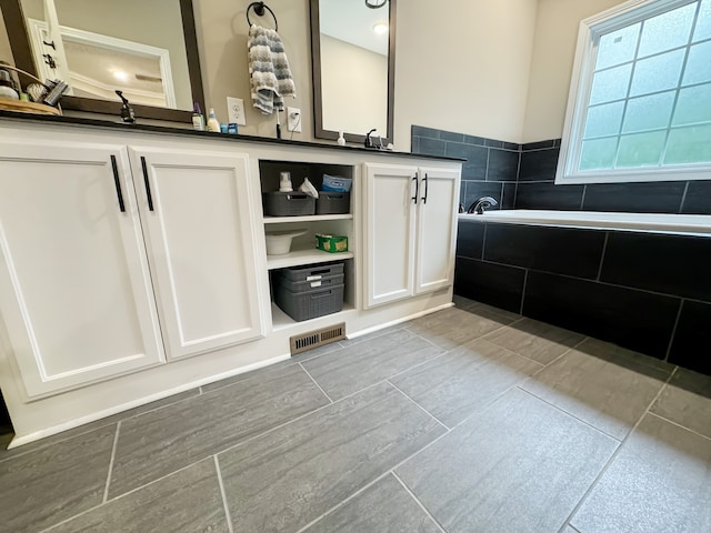 bathroom with vanity and tiled bath