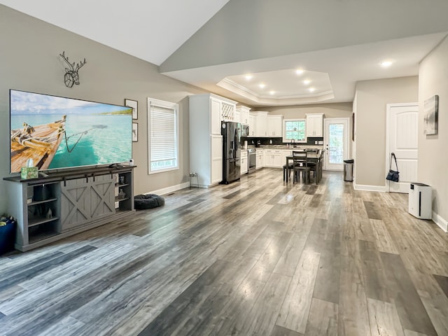 kitchen featuring stainless steel fridge, a tray ceiling, sink, hardwood / wood-style flooring, and white cabinetry