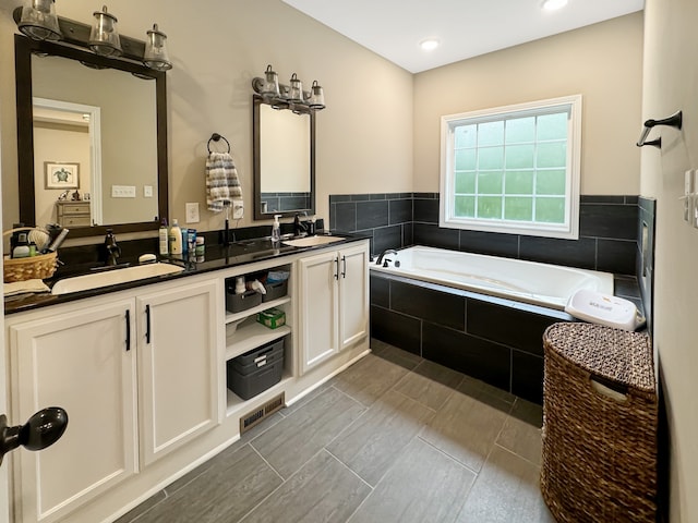 bathroom with tiled bath and vanity