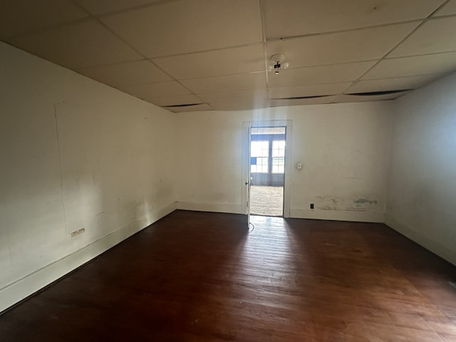 spare room featuring dark wood-type flooring and a drop ceiling