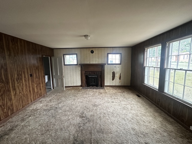 unfurnished living room featuring wood walls and light carpet