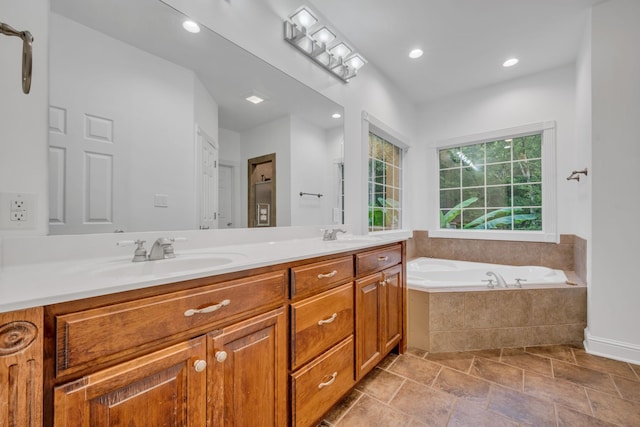 bathroom featuring tiled tub and vanity