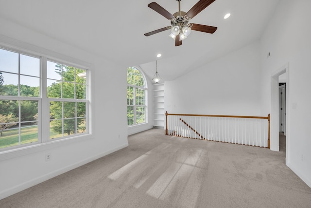 unfurnished room with lofted ceiling, light colored carpet, and built in shelves