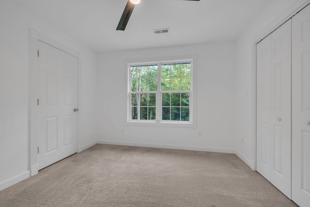 unfurnished bedroom featuring light carpet, a closet, and ceiling fan