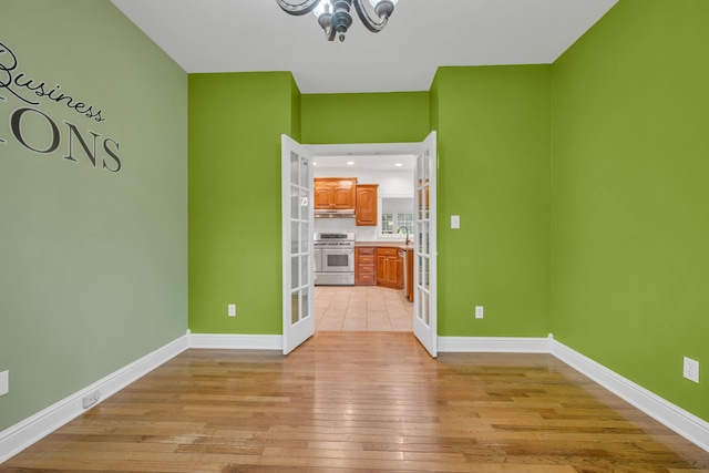 interior space featuring french doors, sink, light hardwood / wood-style floors, and a notable chandelier