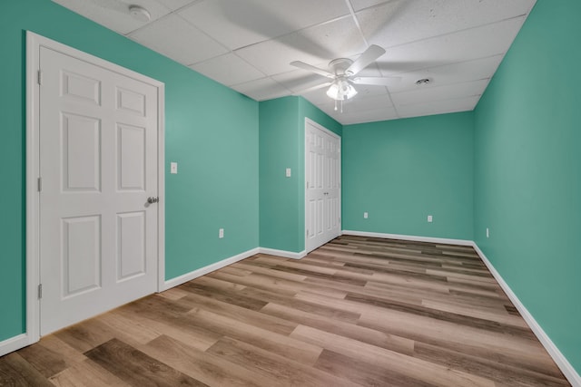 unfurnished bedroom featuring a drop ceiling, light hardwood / wood-style flooring, a closet, and ceiling fan