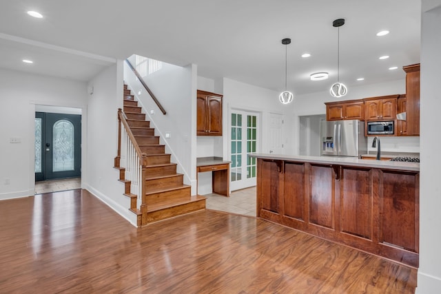 kitchen with sink, appliances with stainless steel finishes, a kitchen bar, kitchen peninsula, and light wood-type flooring