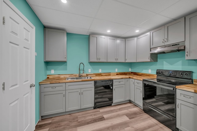 kitchen featuring sink, gray cabinets, light hardwood / wood-style flooring, black appliances, and wood counters