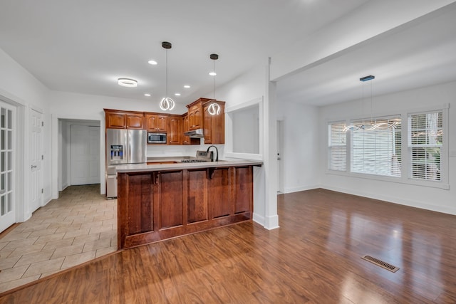 kitchen with sink, stainless steel appliances, decorative light fixtures, kitchen peninsula, and light wood-type flooring