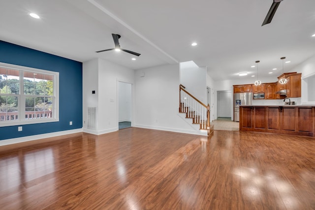 unfurnished living room with ceiling fan, sink, and light hardwood / wood-style flooring