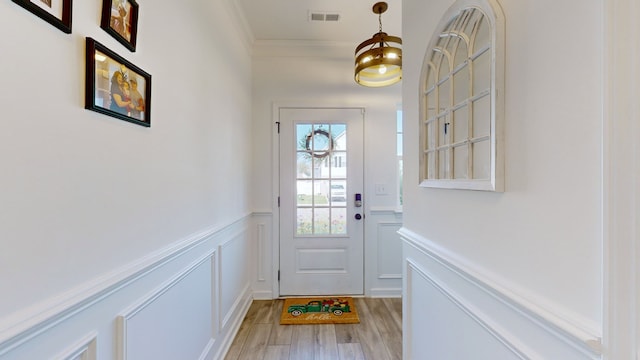 entryway with light hardwood / wood-style floors and crown molding