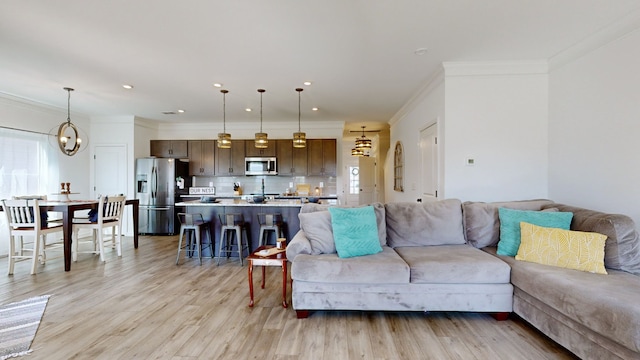 living room with ornamental molding, light hardwood / wood-style flooring, and a notable chandelier