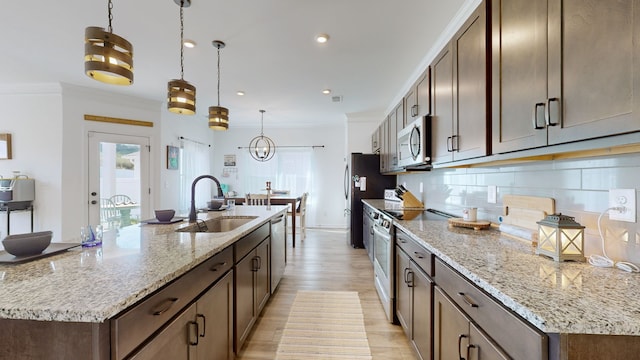 kitchen featuring sink, decorative light fixtures, appliances with stainless steel finishes, light stone countertops, and decorative backsplash