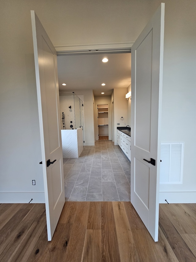 corridor featuring light wood-type flooring and sink